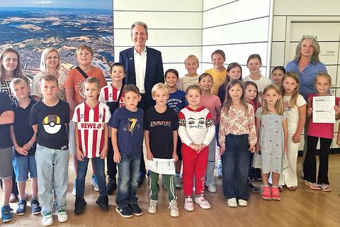 Alle Ferienkinder in Startstellung zur Rathaus-Rallye mit Bürgermeister Dr. Ralf Göck und Marion Thüning (rechts), gesamtverantwortlich für das Kinderferienprogramm 2025, und Marie Schäfer mit Ivona Szutra im Sitzungssaal des Rathauses